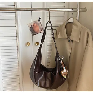 Close-up of a large brown faux leather hobo bag with a cute bear plush charm