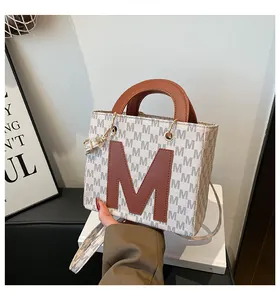 Detail of a vintage mini tote bag with letter monogram print and brown leather M logo