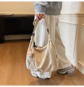 Detail of beige canvas shoulder bag featuring a cute brown plush bear charm and spacious design