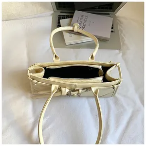 Beige tote bag with laptop and books showing interior zipper compartment