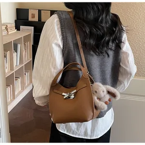 Caramel bucket bag in lychee leather featuring a silver buckle and plush rabbit charm