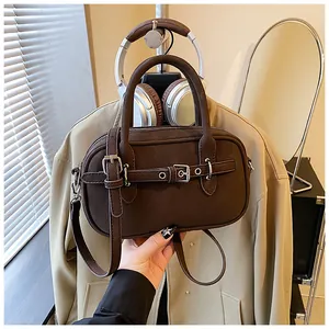Close-up of a dark brown crossbody bag featuring dual strap buckles and cylindrical handles