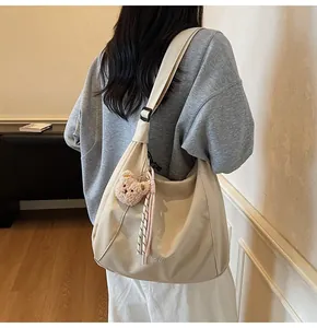 Back view of beige crossbody bag with plush bear charm and striped tassel detail