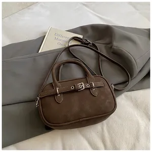 Detail of dark brown leather handbag with buckle strap on vintage blazer background