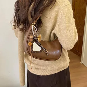 Vue détaillée d'un sac demi-lune marron avec miroir cœur léopard et pendentifs en peluche