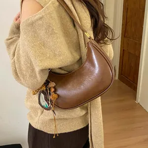 Détail d'un sac hobo croissant marron avec texture cuir vintage et breloque peluche