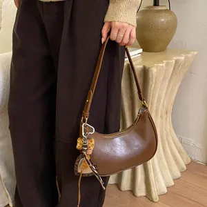 Détail d'un sac à bandoulière marron en forme de lune avec breloque cœur léopard