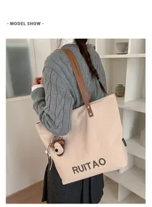 Vue latérale du cabas en toile avec ses anses en cuir marron et son pendentif chien