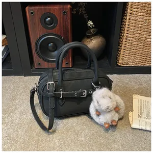 Close-up of black retro handbag with leather texture, silver buckle, and plush rabbit charm