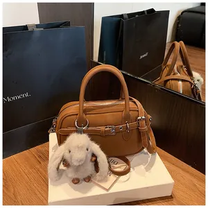 Detail of caramel brown leather handbag with pebble texture and plush bunny charm