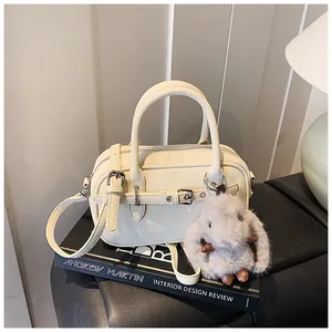 Detail view of cream lychee texture handbag with double handles and cute rabbit charm