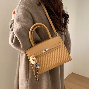 Detail of camel crossbody bag featuring woven texture mix and cute cat plush charm