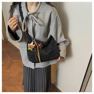 Detail of a black half-moon crossbody bag featuring cute bear and star charms on the strap