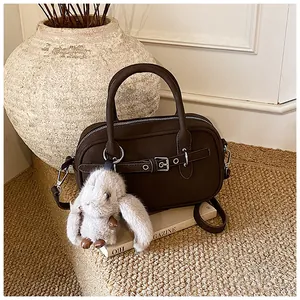Detail of dark brown leather Boston bag with silver hardware and a plush rabbit pendant
