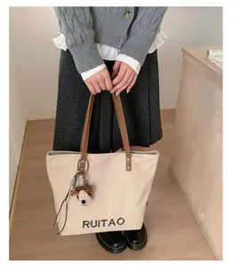 Détail du cabas en toile avec broderie RUITAO et anses en cuir porté par le mannequin