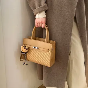 Detail of khaki leather bag featuring woven panel, turn-lock and leopard plush charm