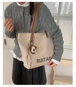 Détail du sac fourre-tout beige en toile avec sangle en cuir et breloque chien