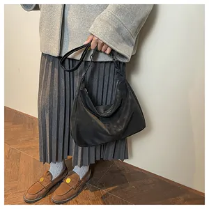 Minimalist black crescent hobo bag with adjustable strap paired with a grey wool coat