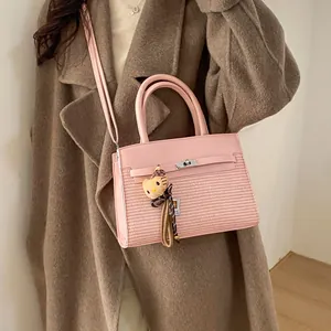 Pink stitched small square handbag with woven texture and cute plush charm on model