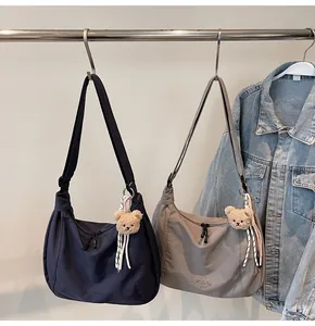 Detail of minimalist nylon hobo bags in blue and taupe with cute bear charms