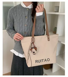 Sac fourre-tout beige avec broderie RUITAO et lanières brunes porté par un mannequin