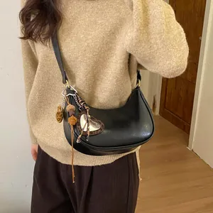 Détail du sac demi-lune noir avec pendentif cœur léopard et finitions à pompons élégants