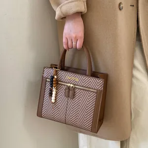 Gros plan du sac à main en cuir PU marron avec motif à chevrons et breloque en perles