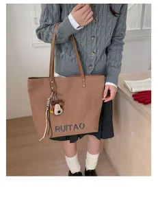 Gros plan sur un sac cabas marron avec lettres brodées et charmant pendentif chiot
