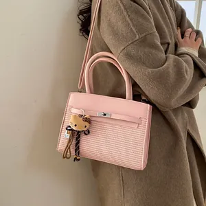 Detailed close-up of pink patchwork handbag with woven texture and cute plush kitten charm