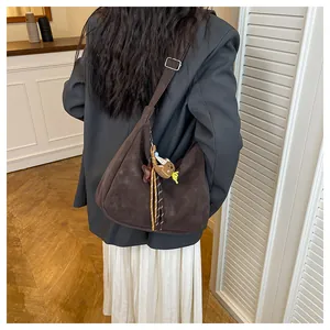 Detail view of a vintage dark brown shoulder bag with teddy bear charm on model back