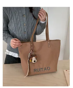 Détail de la broderie RUITAO sur tote bag marron avec pendentif chien en peluche