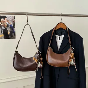 Détail de sacs hobo croissants en cuir marron avec breloques d'ours en motif léopard