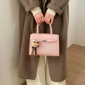 Detail of pink leather handbag with woven texture and cute character plush charm