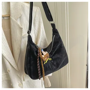 Detail of black matte crossbody hobo bag with silver zipper and brown bear pendant