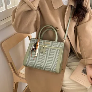 Détail du sac bandoulière vert sauge avec tissu à chevrons et breloque en perles