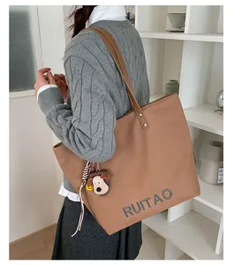 Détail d'un sac cabas en toile marron avec broderie de lettres et pendentif chien mignon