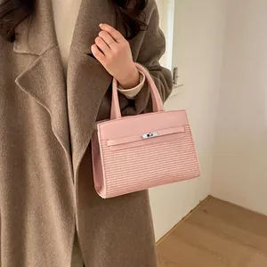 Detail of pink woven leather handbag with silver lock shown on a model in a coat