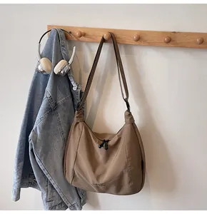 Detail of a brown nylon crossbody bag with dual zipper and adjustable shoulder strap