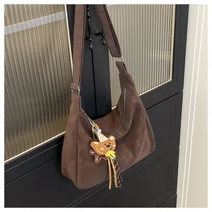 Detail of a dark brown suede Hobo shoulder bag featuring a cute cartoon bear pendant