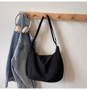 Detail of a black crescent shoulder bag with embroidery on a textured fabric surface