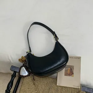 Détail du sac bandoulière croissant noir avec fermeture dorée et breloque miroir cœur