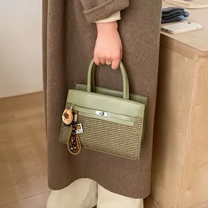 Close-up of olive green handbag with metallic lock and cute cat charm in a lifestyle setting