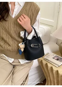 Detail of black lychee grain bucket bag with silver buckle and cute blue bear plush charm