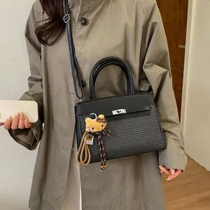 Detail of black leather and woven bag with silver turn-lock and plush charm
