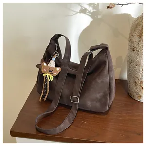 Detail of dark brown shoulder bag with a cute bear charm on a vintage wooden desk