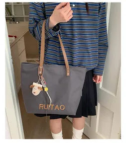Détail du sac cabas en toile gris foncé avec broderie RUITAO et breloque chien en peluche