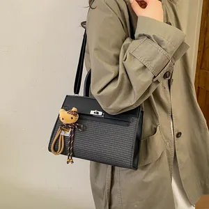 Detail of a contrast paneled handbag with a plush cat charm and silver twist lock