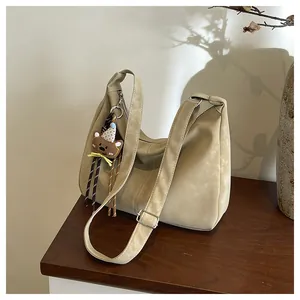 Detail of beige shoulder bag featuring soft PU leather and cute bear charm on wooden table