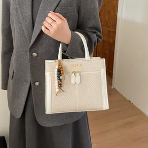 Détail d'un sac à main tissé avec perles en bois et logo JINGPIN sur blazer gris