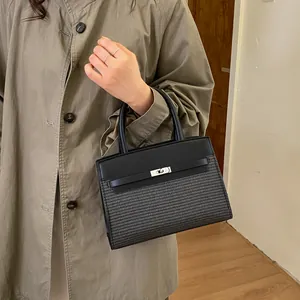 Detail of black Kelly style handbag showing textured leather contrast and silver clasp
